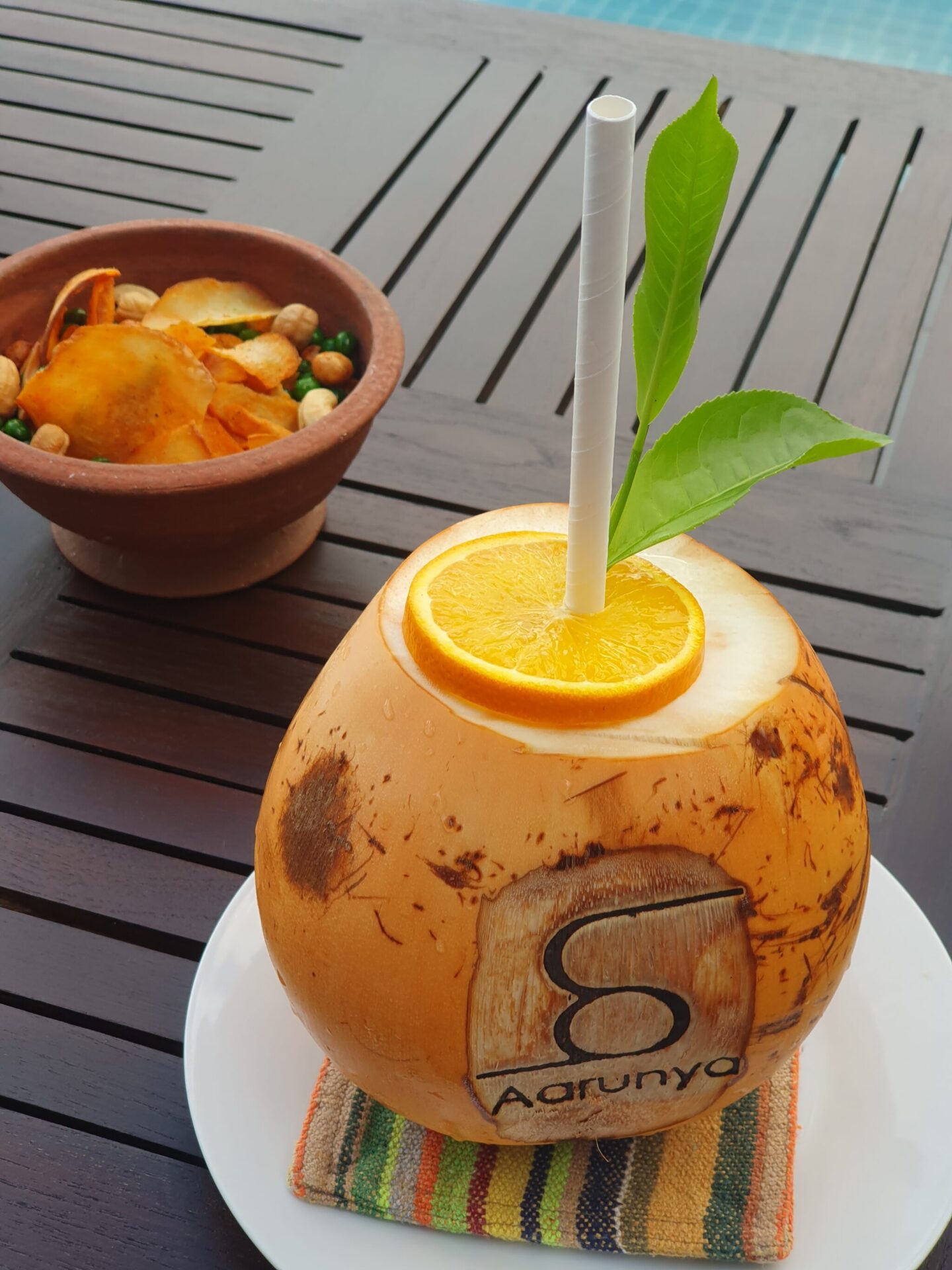 Fresh coconut cocktail served at Aarunya with the resort’s name printed on the shell and a homemade savoury snack