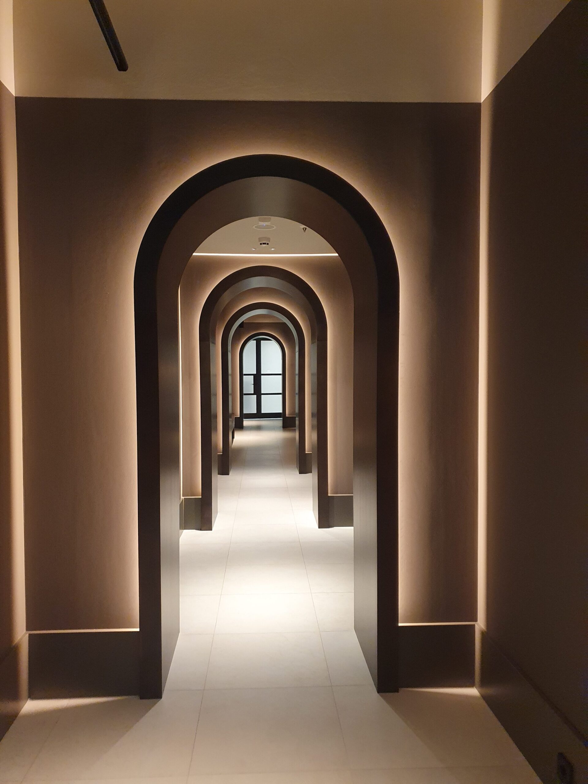 Elegant hallway at Rosewood Amsterdam featuring a series of arches creating a layered, tunnel-like perspective