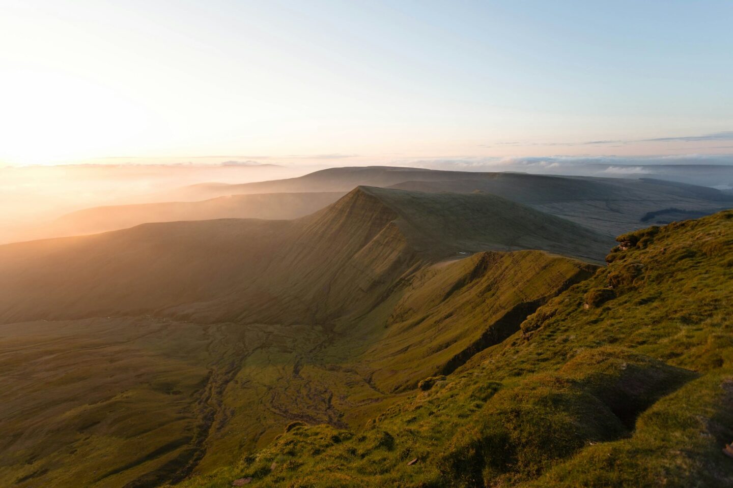 Aerial view of the Brecon Beacons glowing under golden hour light in South Wales